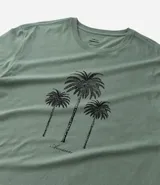 Remera verde oliva de algodón, corte comfort, cuello redondo y manga corta. Estampado frontal con tres palmeras negras y texto inferior.