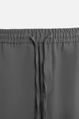 Pantalón color arena de corte recto, confeccionado en tejido elástico. Cuenta con cintura elástica ajustable con cordón, bolsillos laterales y bolsillos de vivo en la parte trasera.