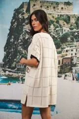 Vestido corto negro con patrón calado cuadrado, cuello redondo y mangas cortas con terminaciones a contratono en blanco.