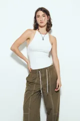 Pantalón tipo babucha negro de tiro bajo con costuras visibles en contraste blanco. Presenta cintura elástica con lazo ajustable blanco y silueta amplia con caída relajada.