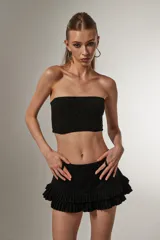 Top cropped negro de poliamida y lurex, al cuerpo, con elástico y cuello strapless.