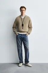 Jersey de hombre color beige, de corte relaxed fit, tejido en hilatura con algodón y ramio. Tiene cuello pico, manga larga y acabados en rib.