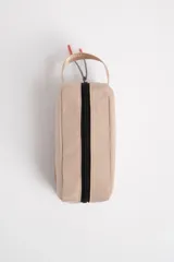 Necesser rectangular color beige con cierre superior negro, asa lateral y parche con logo de estrella.
