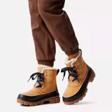 Bota de gamuza color marrón claro con detalles en negro, cordones de trekking y cuello de piel sintética.