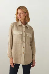 Camisa estilo leñador color beige con detalles en crudo, de manga larga con puños abotonados, cuello camisero, cierre frontal con botones y bolsillos de parche en el pecho.