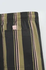 Bañador corto de tejido técnico con rayas verticales en tonos negro, verde oliva y rosa. Cuenta con cintura elástica ajustable con cordón, bolsillos laterales y trasero.