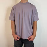 Remera lila con estampado en la espalda que incluye texto, un logo y un diseño geométrico.