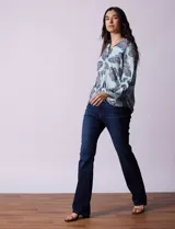 Camisa de gasa estampada a rayas verticales de color celeste, blanco, naranja y marrón. Tiene cuello con solapa, escote en V, abertura central con botones, bolsillo aplicado en el pecho y terminación anudada en la parte delantera.