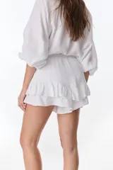 Short pollera blanco de tela arrugada con volados y detalles de encaje.