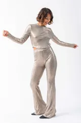 Conjunto de remera corta de mangas largas y pantalón acampanado, ambos de tejido brillante color dorado.