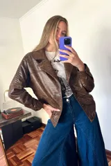 Campera bomber de cuero marrón veteado con cuello desmontable de corderito crudo y detalle de pasamanería en las mangas.