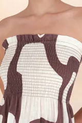 Vestido largo sin mangas, con escote recto y parte superior fruncida con elástico. Estampado abstracto en tonos marrón y blanco.