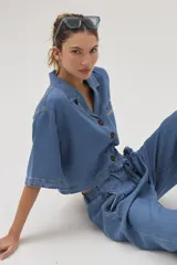 Blusa celeste de denim con cuello camisero, mangas cortas y cierre frontal con botones.