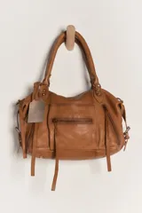 Bolso de mano tipo satchel, color marrón cuero lavado, con asas superiores y múltiples cierres y bolsillos exteriores con cremallera. Incluye un dije colgante metálico con logo grabado.