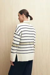 Sweater de rayas horizontales color crudo y marrón, con cuello redondo a contratono color beige, tajos laterales y mangas largas con puño ancho.