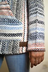 Buzo con capucha de tejido tipo poncho con diseño geométrico multicolor.