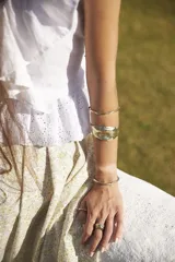 Brazalete rígido abierto de metal color plateado con textura irregular.