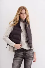 Chaleco puffer negro con cuello alto y cordón de ajuste en el ruedo.