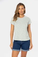 Remera color crema con estampado de hojas azules, de manga corta y cuello redondo.