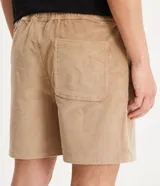 Bermuda masculina tipo runner color beige, confeccionada en terciopelo acanalado, con cintura elástica, cordón de ajuste y bolsillos laterales.