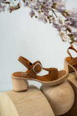 Sandalias negras de charol con tiras entrecruzadas, hebilla dorada y tacón de madera.