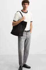 Pantalón de jean celeste de corte slim fit y tapered, con cinco bolsillos, efecto lavado y cierre frontal con cremallera y botón.