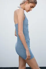 Minivestido celeste de tejido elástico con textura, cuello halter, escote en V, bolsillos simulados y cierre frontal con botones metálicos.