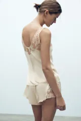 Shorts tipo lencero color crema confeccionado en tejido satinado con tiro alto, cintura elástica y detalle de encaje a tono en el ruedo.