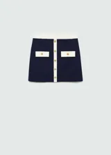 Minifalda azul marino de tejido de punto con ribete blanco en cintura y bolsillos. Presenta dos bolsillos delanteros con solapa y botones dorados decorativos.