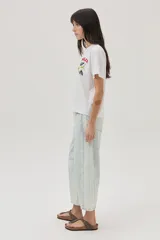 Remera blanca de algodón con cuello redondo y mangas cortas. Estampado en el frente con la palabra "Dolce" en rojo y un diseño floral en negro y verde.