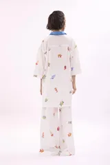 Camisa blanca estampada con dibujos de motivos veraniegos, con cuello clásico y tapeta de botones azul.