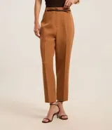 Pantalón de vestir azul marino, de corte zanahoria, con cinturón fino negro con hebilla dorada.