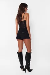 Microshort negro de gabardina elastizada con cierre metálico a la vista en la cartera y bolsillos traseros. En los laterales delanteros presenta cierres metálicos decorativos.