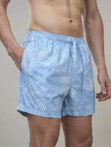 Short de baño verde con estampado de margaritas blancas y cordón ajustable naranja.