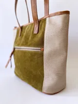 Bolso tipo tote de cuero color verde oliva con laterales de cuero texturizado color beige y manijas de cuero color marrón.
