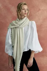 Pashmina color crudo con bordado de líneas negras en los bordes y terminación con flecos.