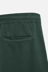 Pantalón largo verde oscuro de algodón con textura, corte recto y cintura elástica ajustable con cordón.