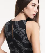 Mono largo sin mangas de viscosa twill color negro con estampado de follaje en blanco. Tiene cuello redondo, cierre con botón en la espalda y bolsillos laterales.
