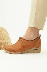 Zapato de cuero color marrón con cierre de cremallera frontal y suela de goma.