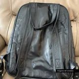 Mochila negra de cuero vacuno con forro de gabardina de algodón, compartimento acolchado para laptop de hasta 14 pulgadas, bolsillo frontal con cierre y cierres metálicos plateados.