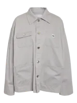 Camisa gris claro de estilo cargo con cuello clásico, cierre de botones, mangas largas y bolsillos utilitarios.