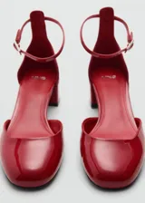 Zapato de tacón bloque color dorado, con punta redonda, efecto charol y cierre de tira con hebilla.