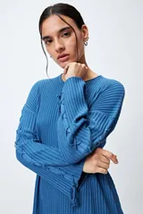 Sweater negro de punto canalé con detalle de trenzado en las mangas y lazo ajustable en el ruedo.