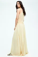 Pollera circular larga color amarillo pálido, de gasa transparente con viso corto. Presenta cintura alta con elástico, tiras finas largas en los laterales y bajo asimétrico con tajo pronunciado en los laterales.