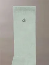 Pack de tres pares de medias Calvin Klein, una blanca, una gris y una verde claro, con logo CK en el tobillo.