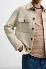 Sobrecamisa color beige de corte recto, con cuello solapa, manga larga con puños abotonados, cierre frontal abotonado, bolsillos de parche con solapa en el pecho y bolsillos de ojal en la cadera.