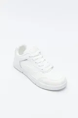 Zapatilla urbana blanca de mujer, con silueta moderna y líneas limpias. Presenta detalles en poliuretano liso y un panel plateado en el talón. La suela es de perfil recto y firme.