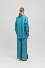 Maxi blusa celeste con estampado floral en tonos grises, mangas caídas, bolsillo de parche y corte oversize.