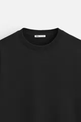 Sudadera negra de corte holgado, cuello redondo y mangas largas con puños acanalados.