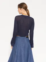 Cardigan azul marino de tejido de lino y algodón, largo hasta la primera cadera. Tiene mangas largas con puños acampanados de tela plana y cierre frontal con botones.